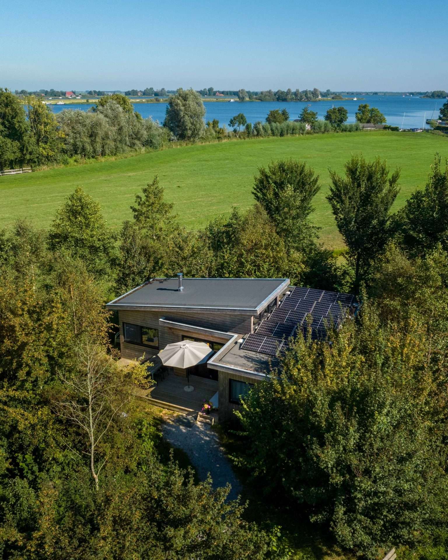 Die Wasserlodge Ljurk von oben, zwischen den Bäumen, mit dem Wasser in der Ferne