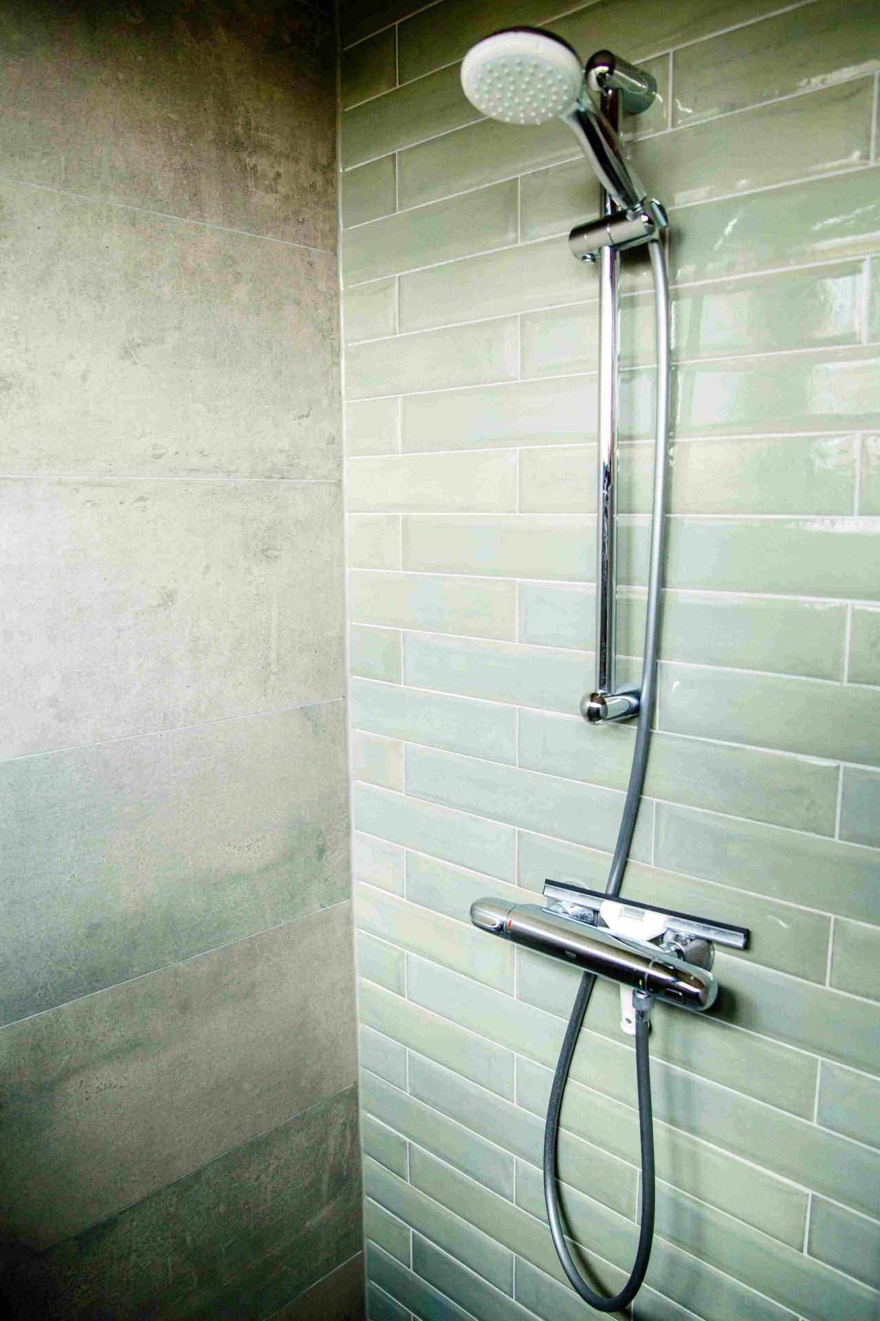 Dusche mit graugrünen Fliesen in der Waterlodge Ljurk