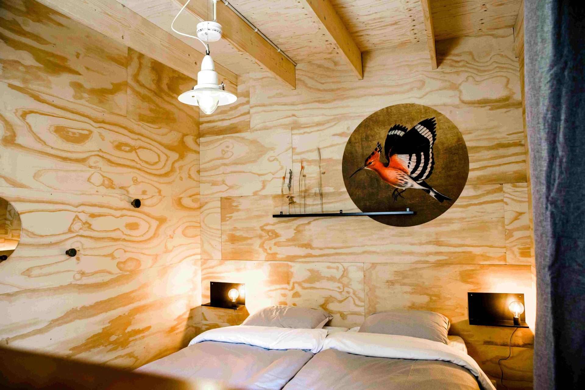 Schlafzimmer in der Waterlodge Ljurk mit Holzwänden und einem Vogelgemälde