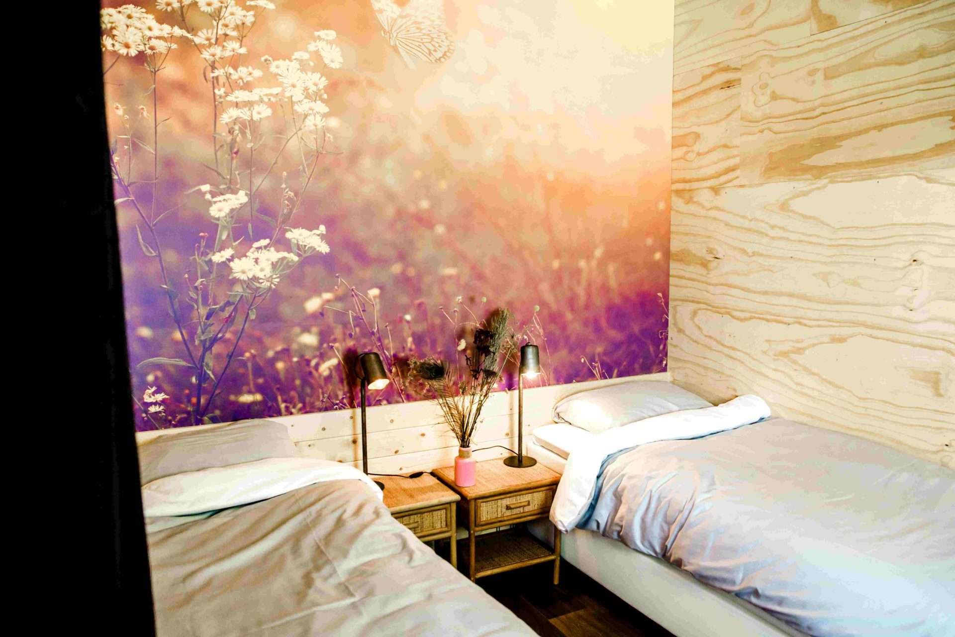 Schlafzimmer in der Waterlodge Ljurk mit zwei Einzelbetten unter floraler Tapete